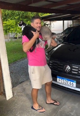Homem segurando dois gatos no ombro
