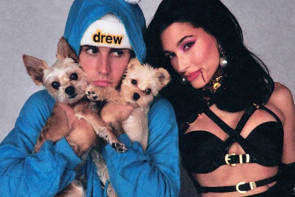 Justin Bieber com casaco azul segurando dois cachorros
