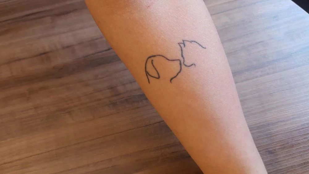 A Júlia é tão apaixonada pelos gatinhos e cachorros que fez uma tatuagem simples para representar todos eles