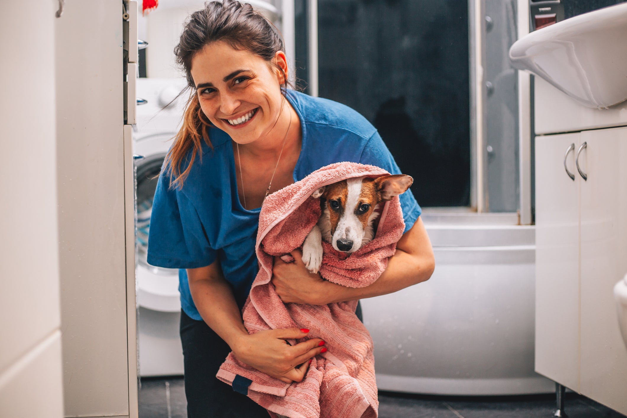 Tutora sorrindo segurando cachorro enrolado em toalha