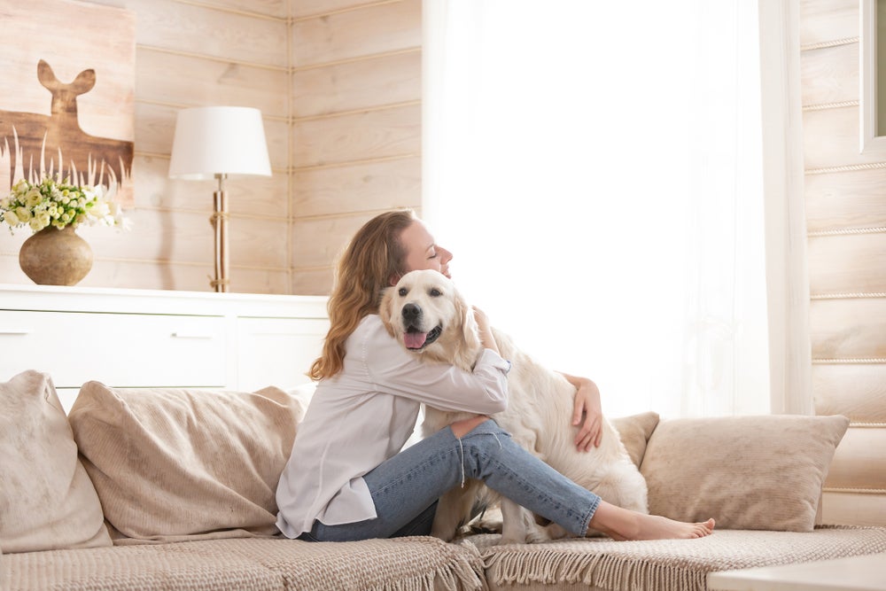 adotar cachorro: mulher abraçando cachorro em cima do sofá