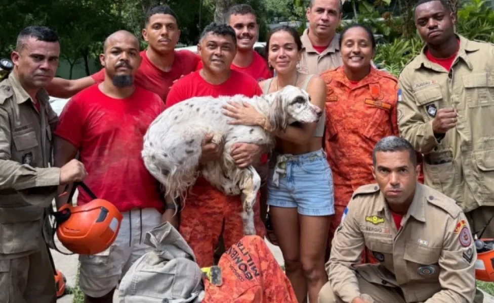Cantora Anitta segurando o cachorro Charlie ao lado de equipe de bombeiros