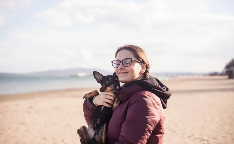 Tutora segurando cão Pinscher preto em praia