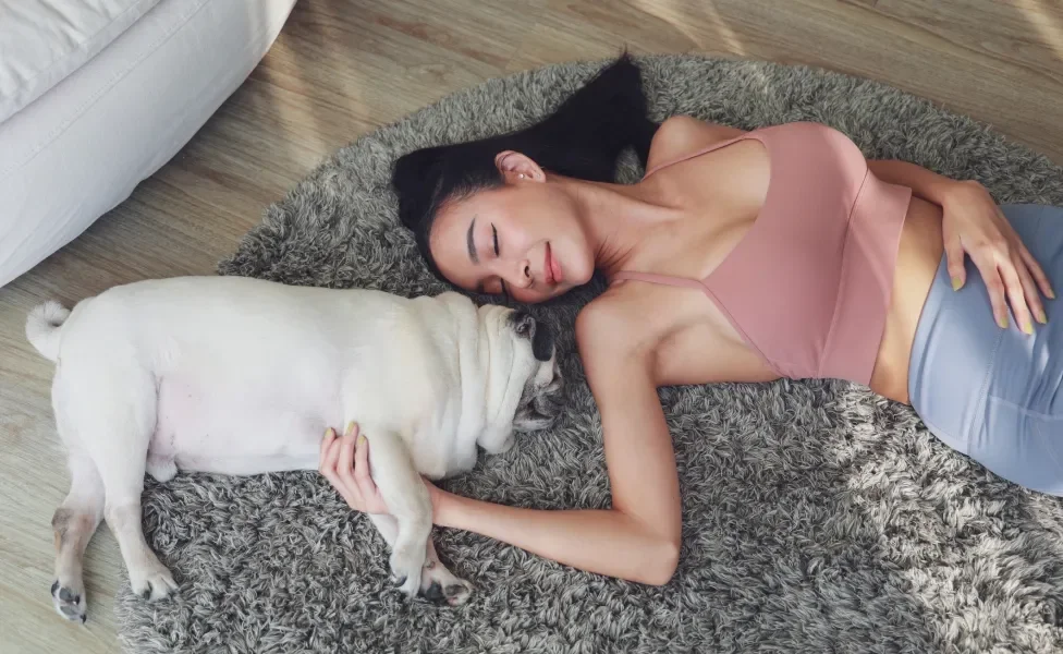 Mulher deitada em tapete junto de seu Pug