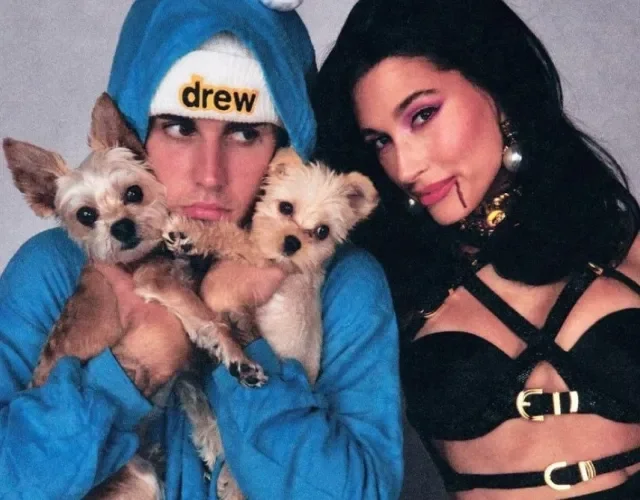 Justin Bieber com casaco azul segurando dois cachorros